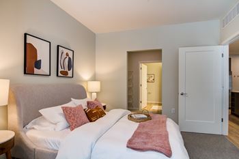 A bedroom with a bed, two lamps, and two pictures on the wall.
